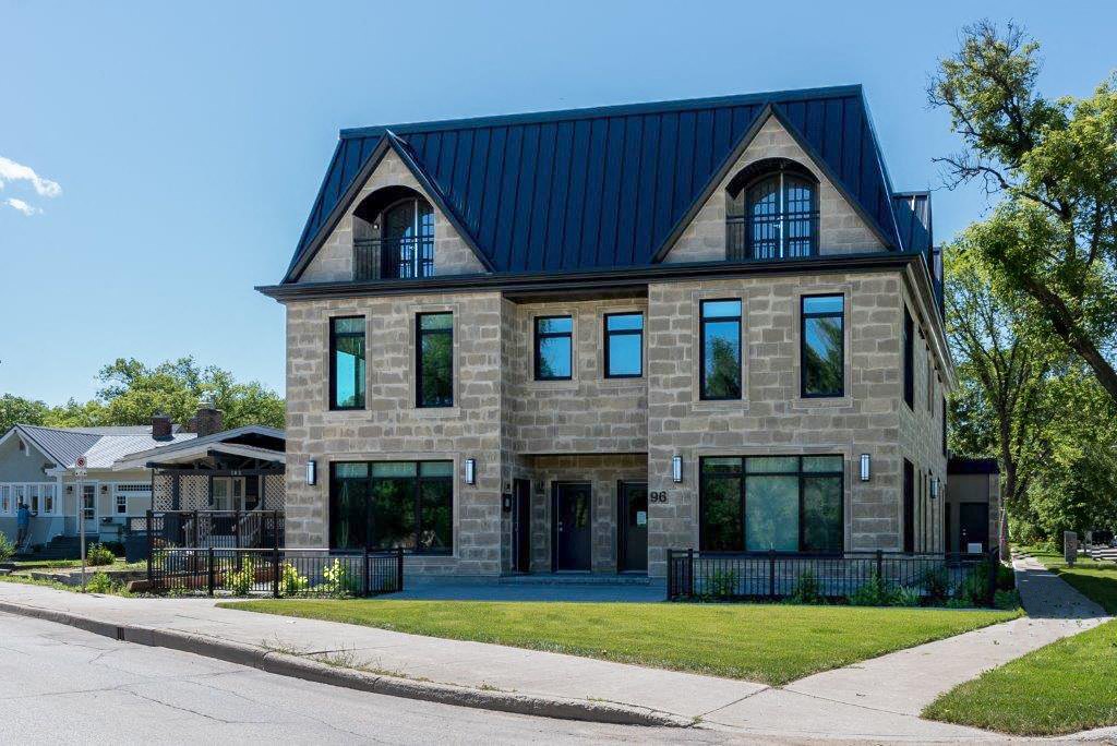 a stone house with a blue roof and a sidewalk